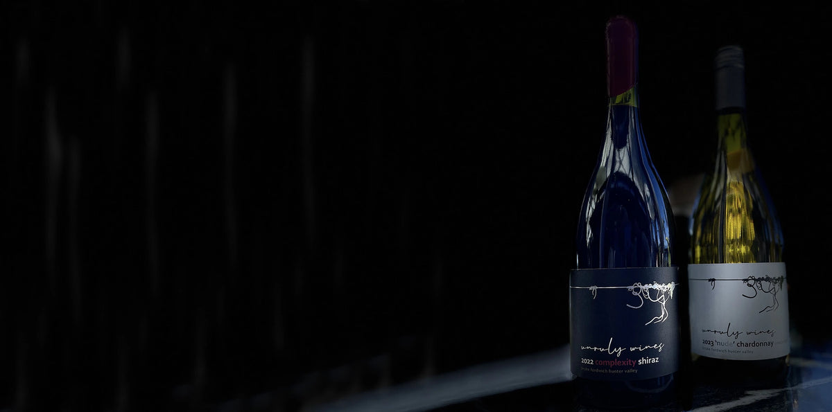 Two bottles of Unruly Wines lit against a dark background